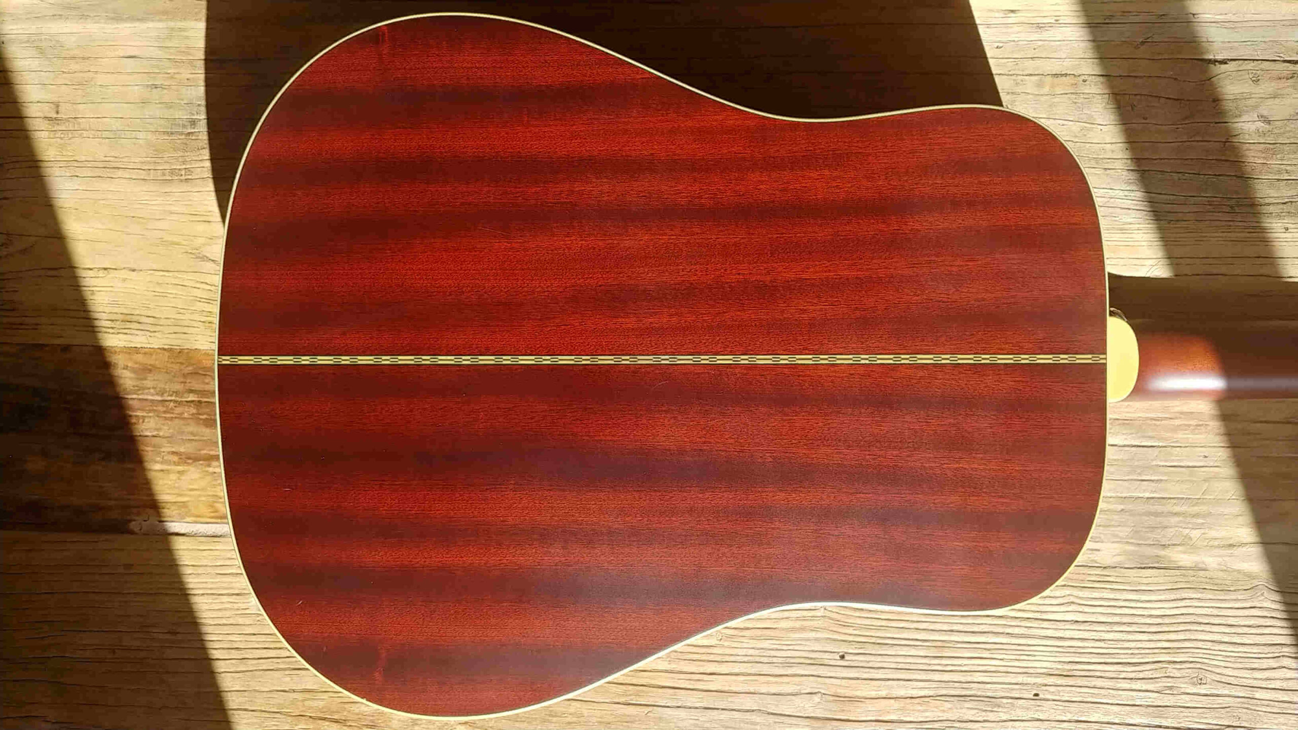 The mahogany back and sides of an Epiphone Masterbilt R-500MNS acoustic guitar.